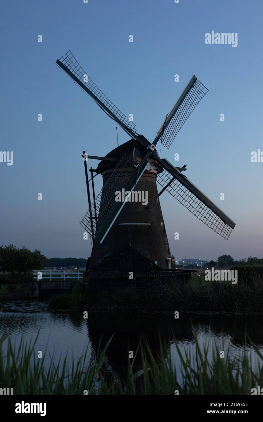 Beautiful wooden windmills at sunset in the Dutch village of Kinderdijk. Windmills run on the wind. The beautiful Dutch canals are filled with water. Stock Photo