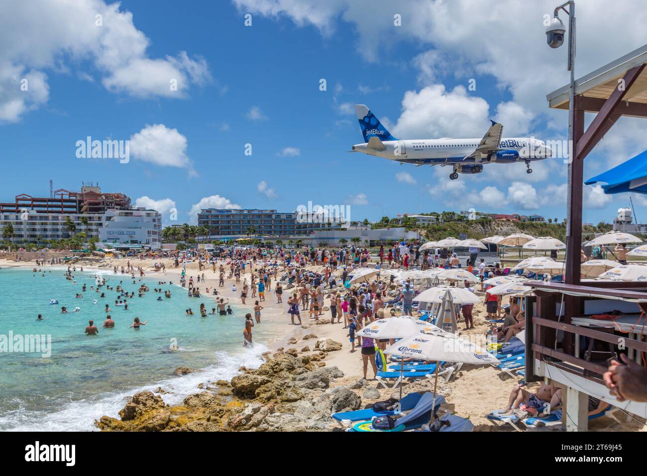 Commercial Jet Blue airliner flying low over Maho Beach on final approach to the Princess Juliana International Airport at St. Maarten Stock Photo