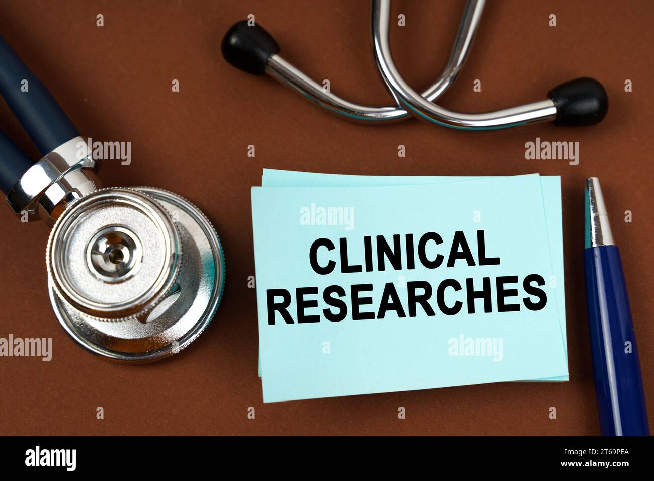 Medical concept. On a brown surface there is a stethoscope, a pen and blue stickers with the inscription - clinical researches Stock Photo
