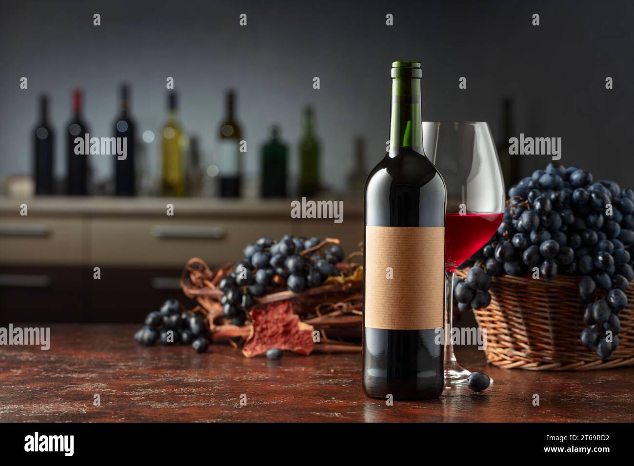 Bottle and glass of red wine with blue grapes on a vintage table. On a ...