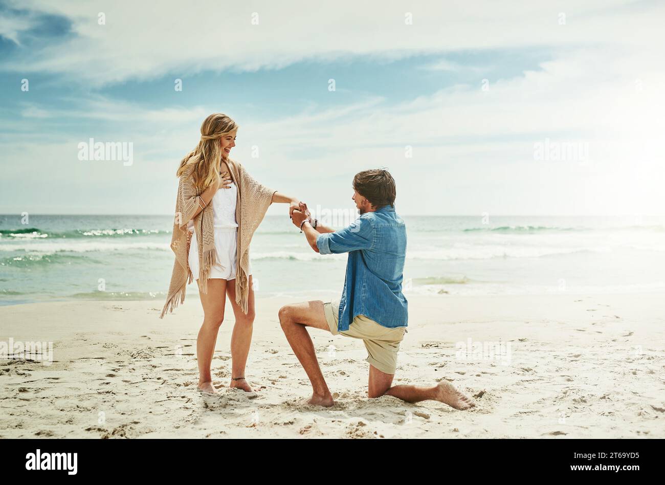 Will you make me the happiest man in the world. Full length shot of a young man proposing to his girlfriend on the beach. Stock Photo