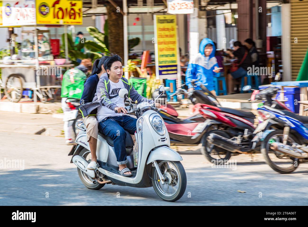Thai couple riding a scooter along Ban Du street in Chiang Rai, Thailand Stock Photo
