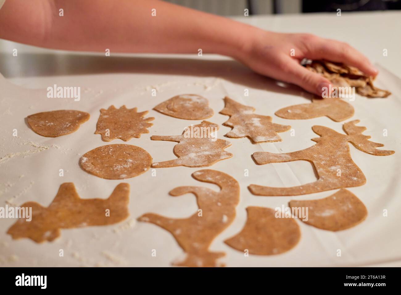 A hand of a kid making gingerbread cookies from dough using different ...