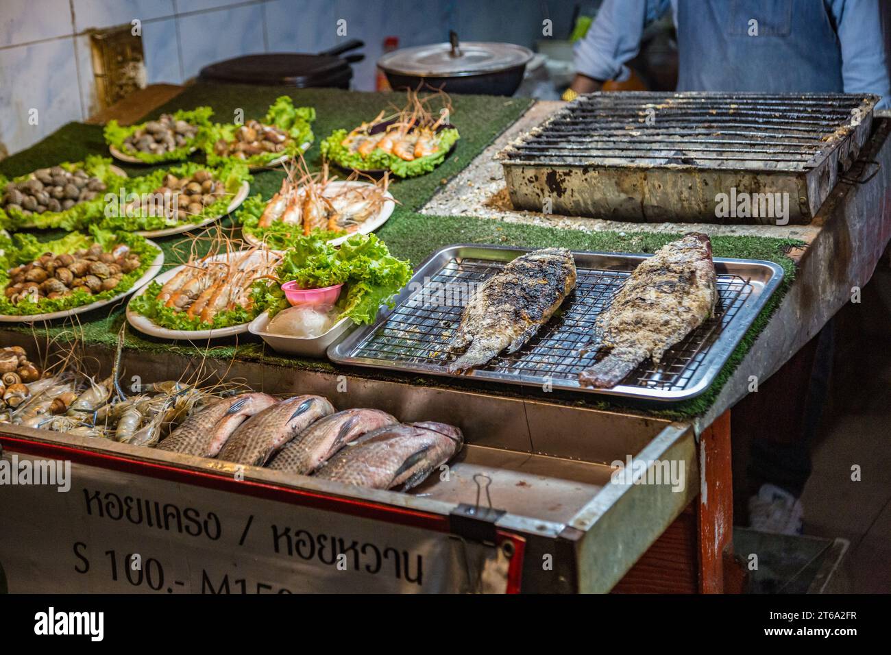 Thai street vendor offers fresh cooked seafood at the night market in downtown Chiang Rai, Thailand Stock Photo