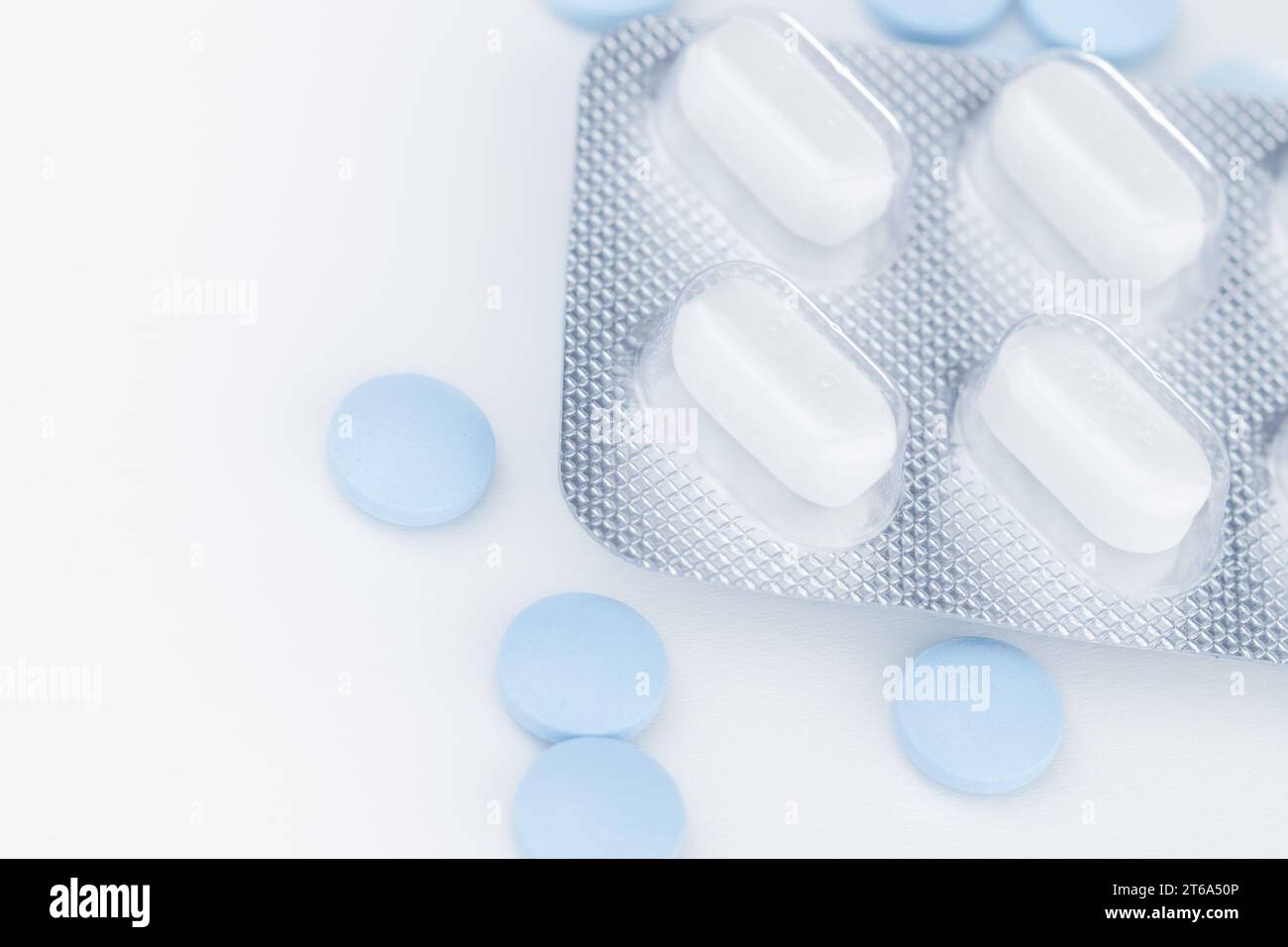 White blister pack pills, pharmaceutical product, many blue pills separately on a white background, close-up and selective focus. Stock Photo