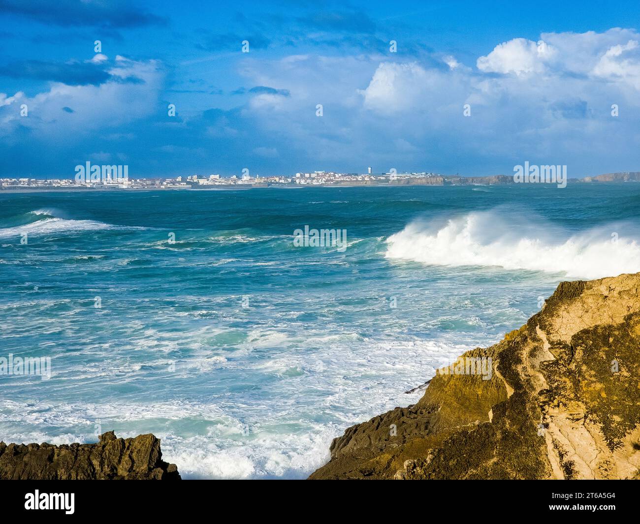 Majestic ocean waves crashing onto rocky shoreline with azure blue sky ...