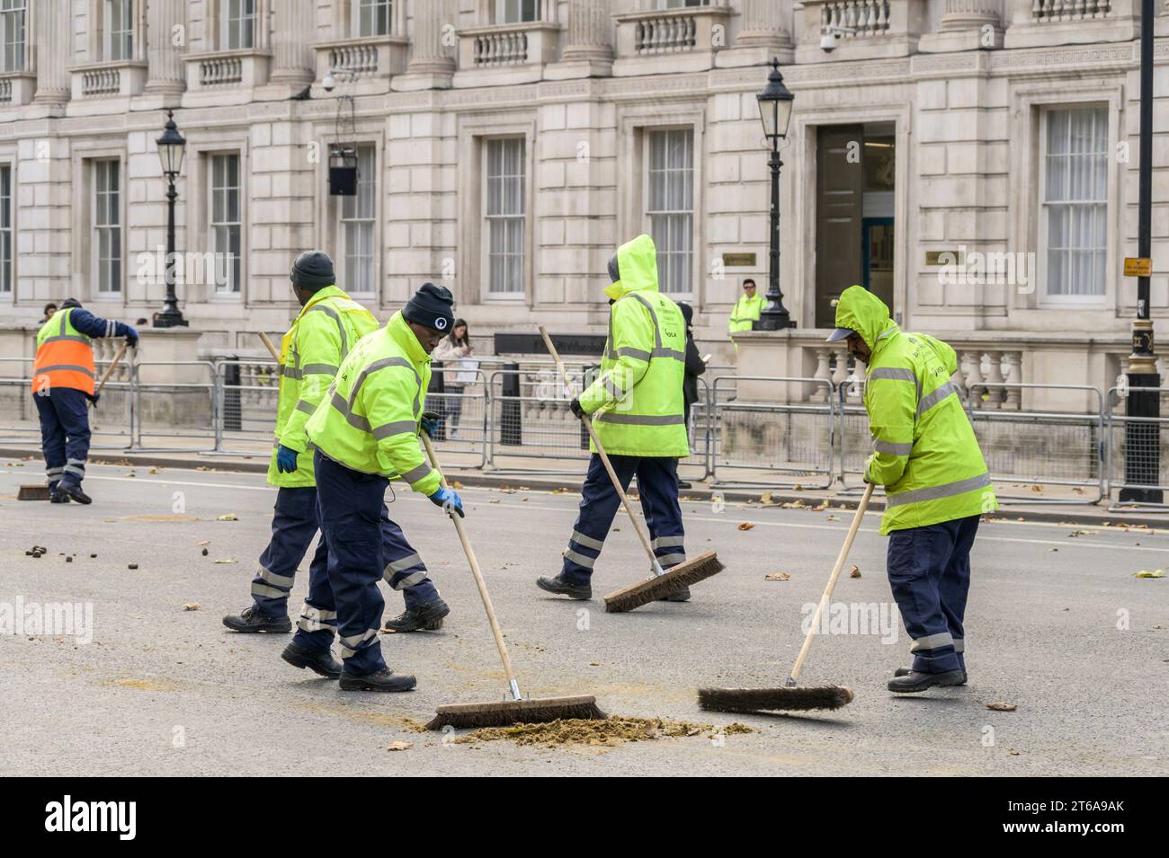 Men in Whitehall, Westminster clear up after the horses following Charles III's first State Opening of Parliament as king. 7th November 2023 Stock Photo
