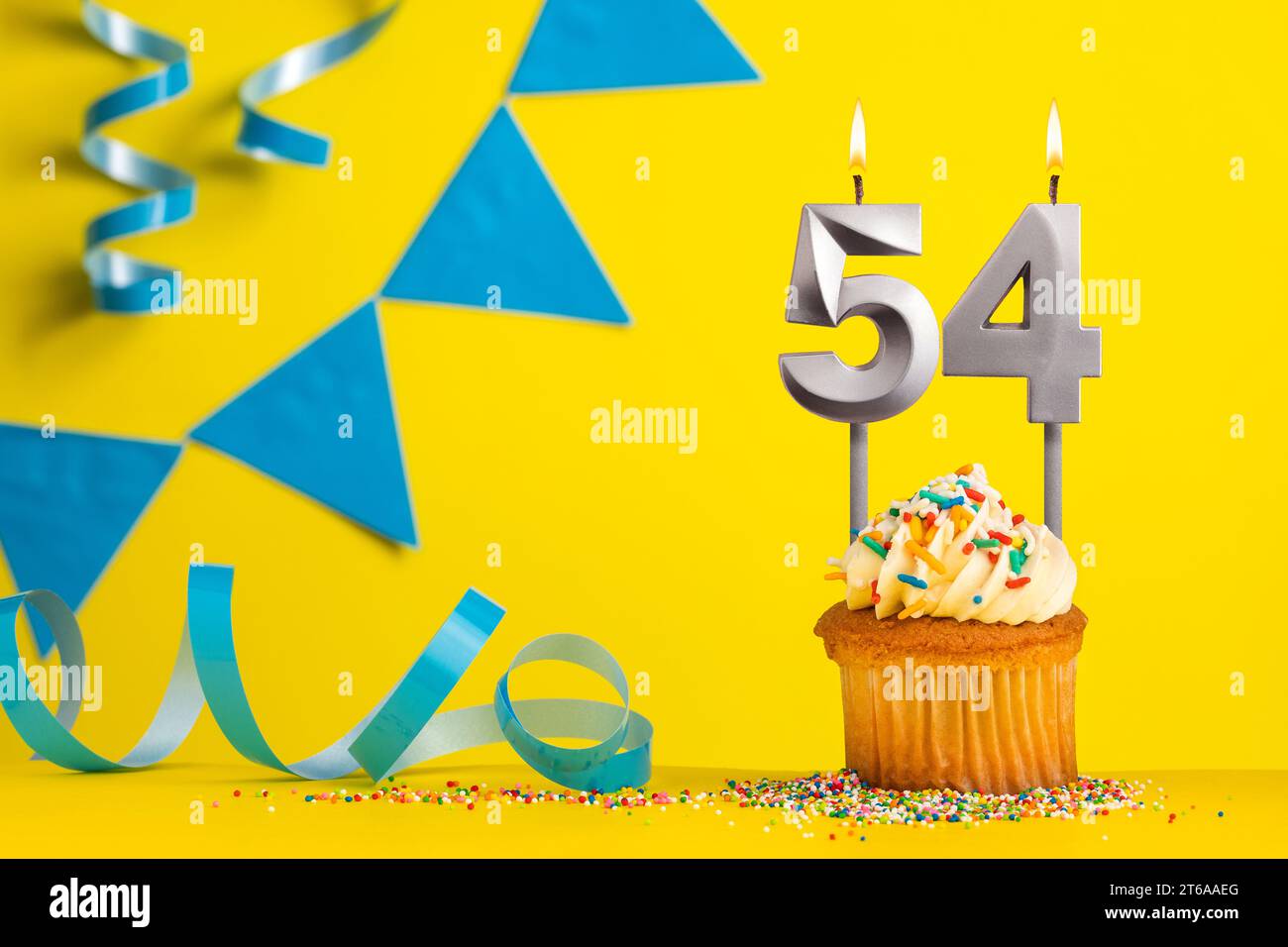 Lighted birthday candle number 54 - Yellow background with blue pennants Stock Photo