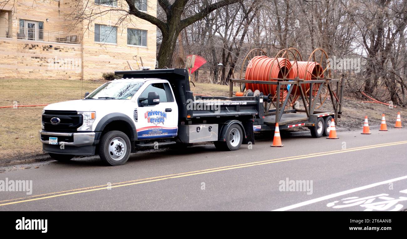 A Universal Services truck carrying large rolls of orange conduit to carry buried electronic cable. St Paul Minnesota MN USA Stock Photo