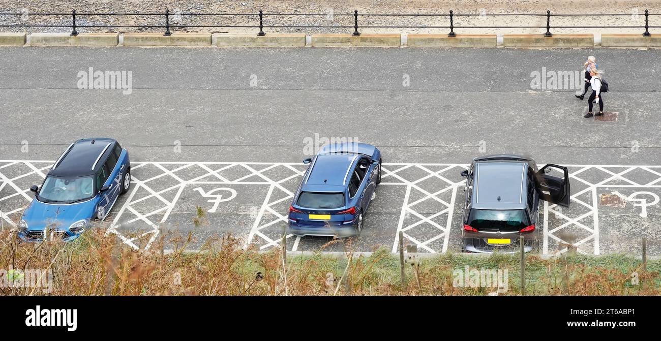 Disabled blue badge holders car parking spaces aerial view of white road markings with wheelchair icon & bay hatching on seaside promenade Norfolk UK Stock Photo