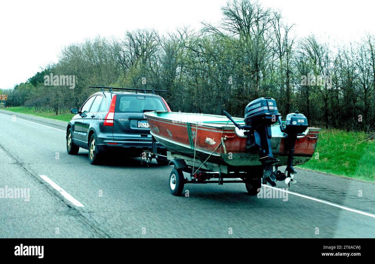 Car hauling Lund aluminum boat with a larger Evinrude outboard motor for speed and a smaller engine for trolling. Minnesota MN USA Stock Photo