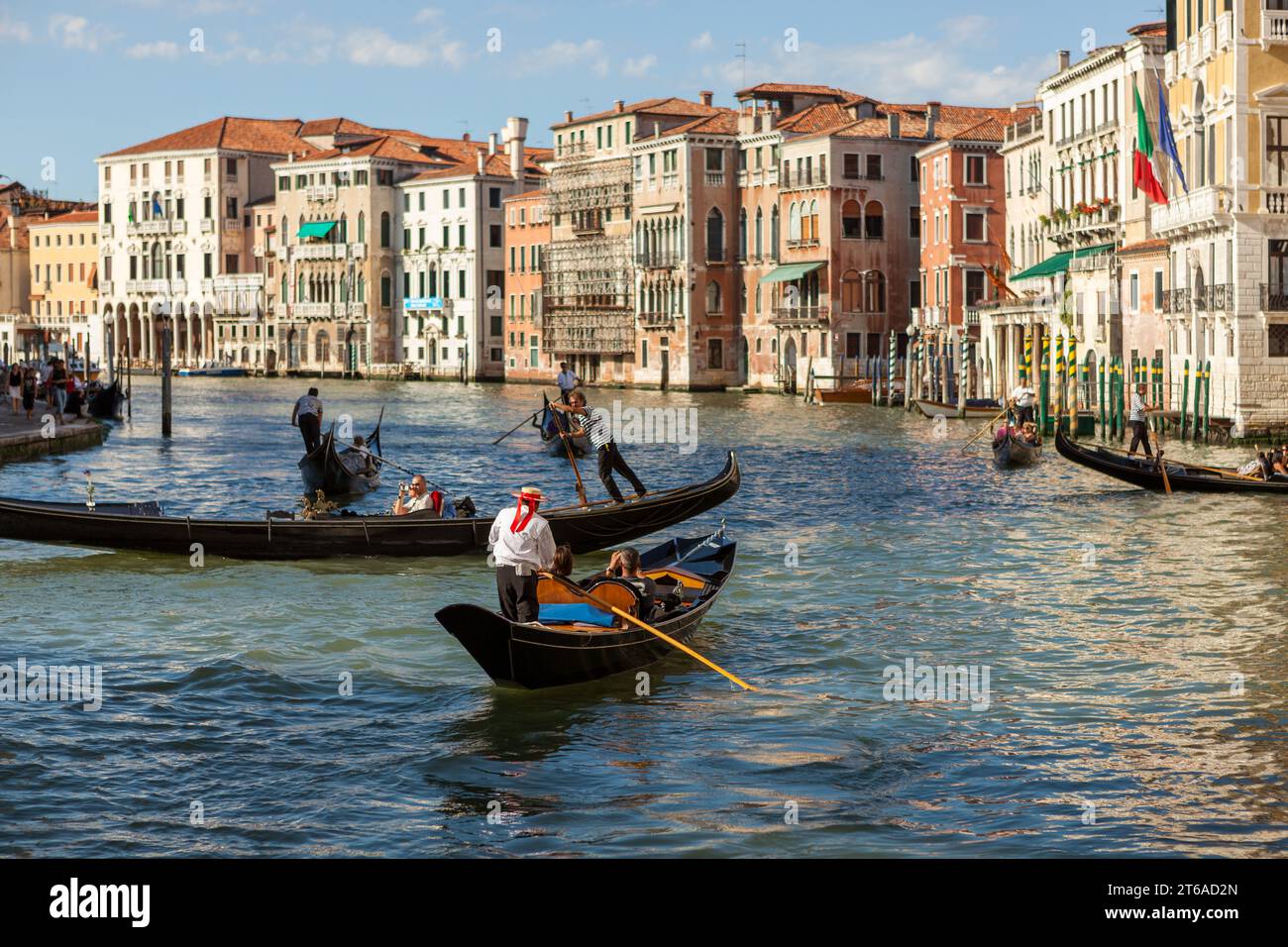 Gondolas carrying tourists on the Grand Canal in Venice in a coordinated movement. Stock Photo