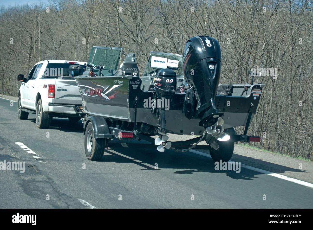 Ford F-150 FX4 pickup truck pulling a Lund 1875  Impact fishing boat with Mercury 110 and 9.9 outboard motors on a trailer. Minnesota MN USA Stock Photo