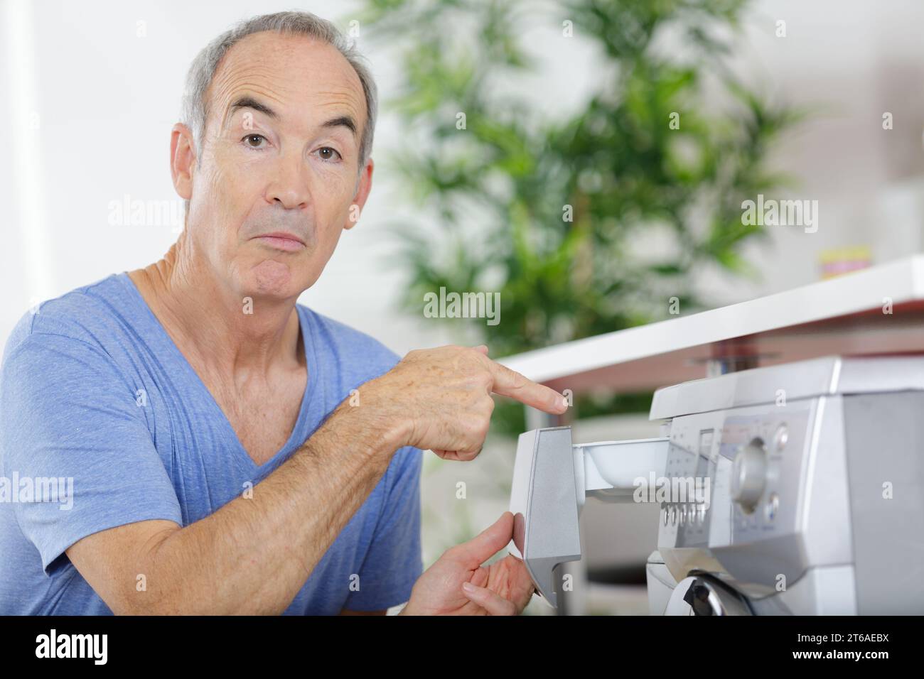 senior man using washing machine Stock Photo