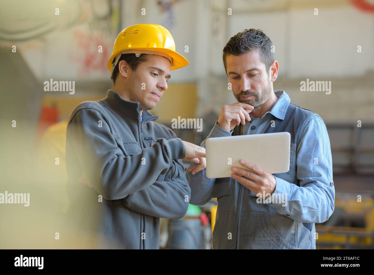 contemplative manual workers looking at digital tablet Stock Photo