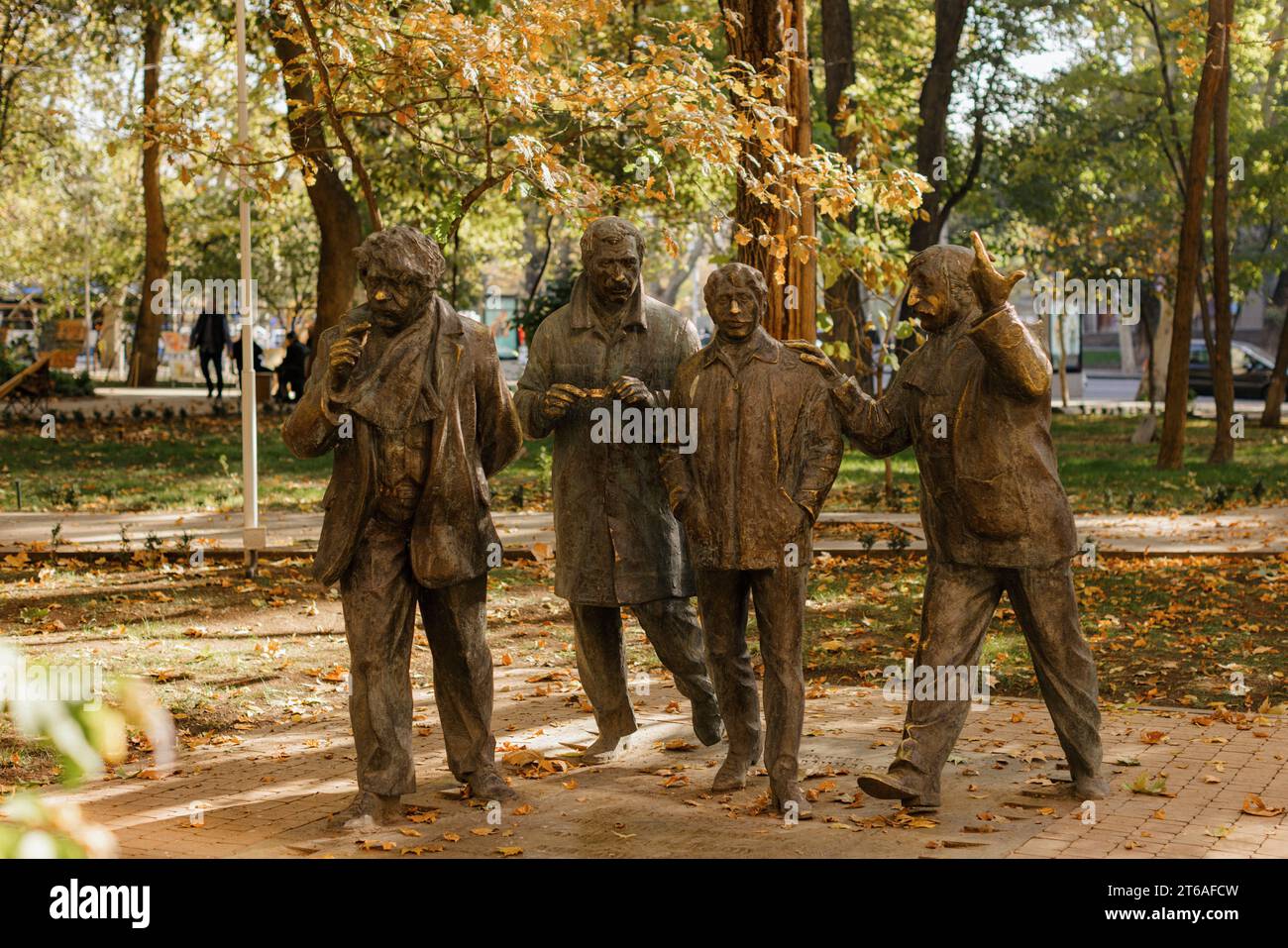 A bronze statue of five men speaking to each other and standing in unison in a park Stock Photo