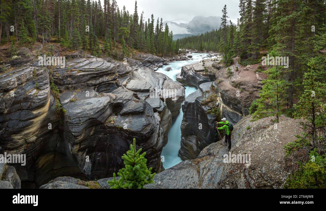 A tourist takes a photo of Mistaya Canyon in Banff National Park ...