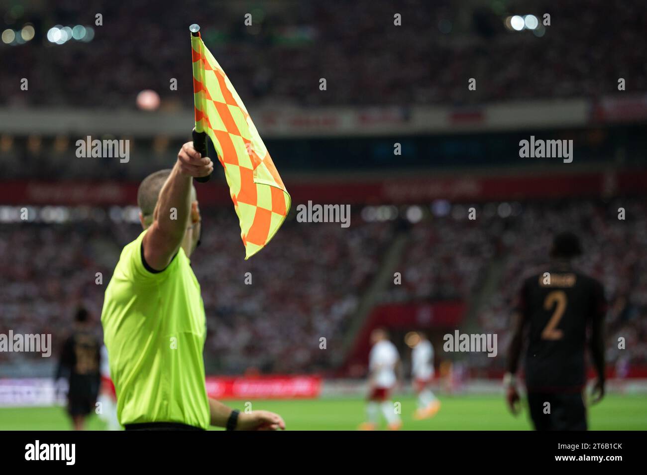 Raised flag of the sideline referee during football match. Stock Photo