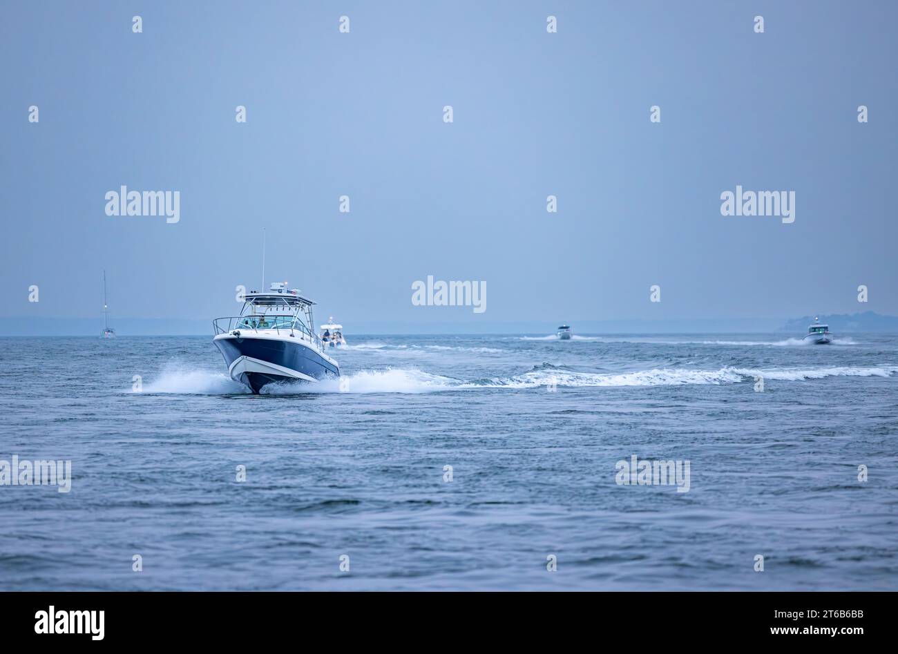 four power boats and a sail boat of the coast of shelter island just before dark Stock Photo