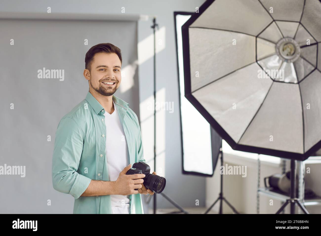 Portrait of handsome photographer posing with his camera in office Stock Photo