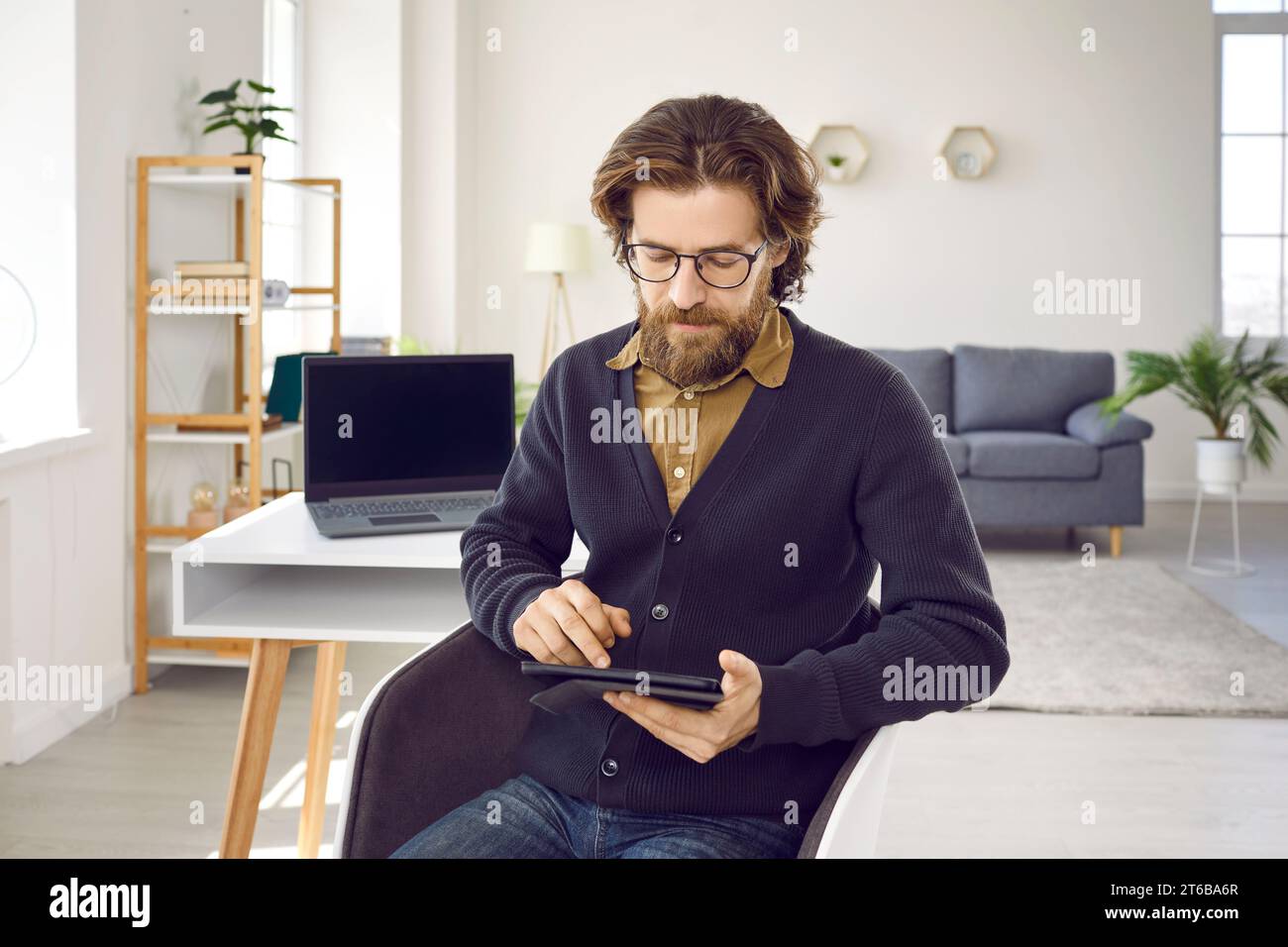 Serious businessman uses some applications to work while working on digital tablet. Stock Photo