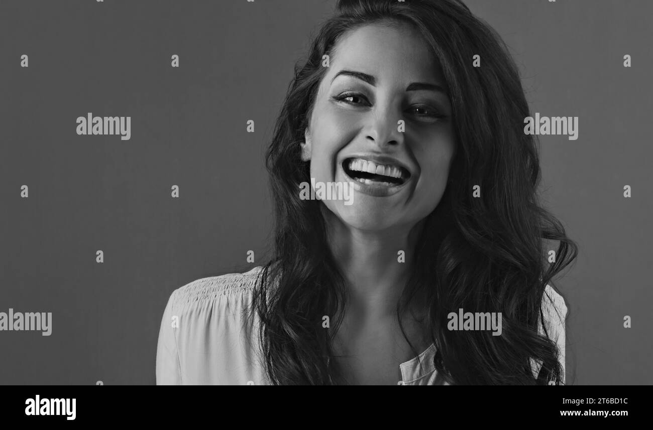 Beautiful business toothy enjoying laughing woman with long brown healthy curly hair style in white shirt clothing. Closeup studio portrait. Black and Stock Photo