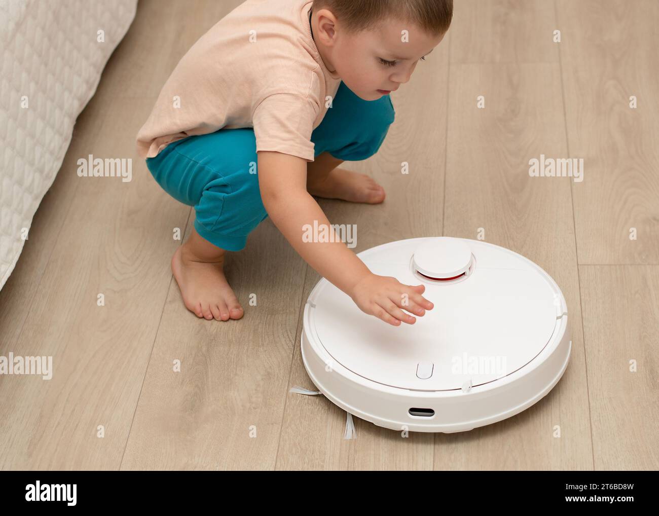 A little cheerful boy in home clothes, throws torn paper into small