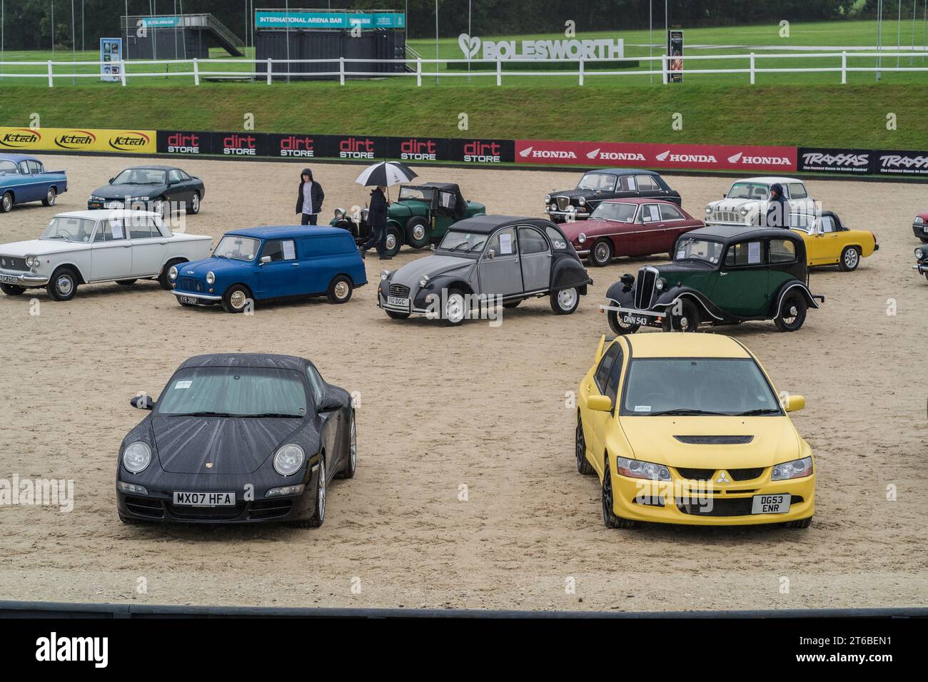 Chester, Cheshire, England, October 1st 2023. Black Porsche 911 and yellow Mitsubishi Evolution VIII at a classic car auction. Stock Photo