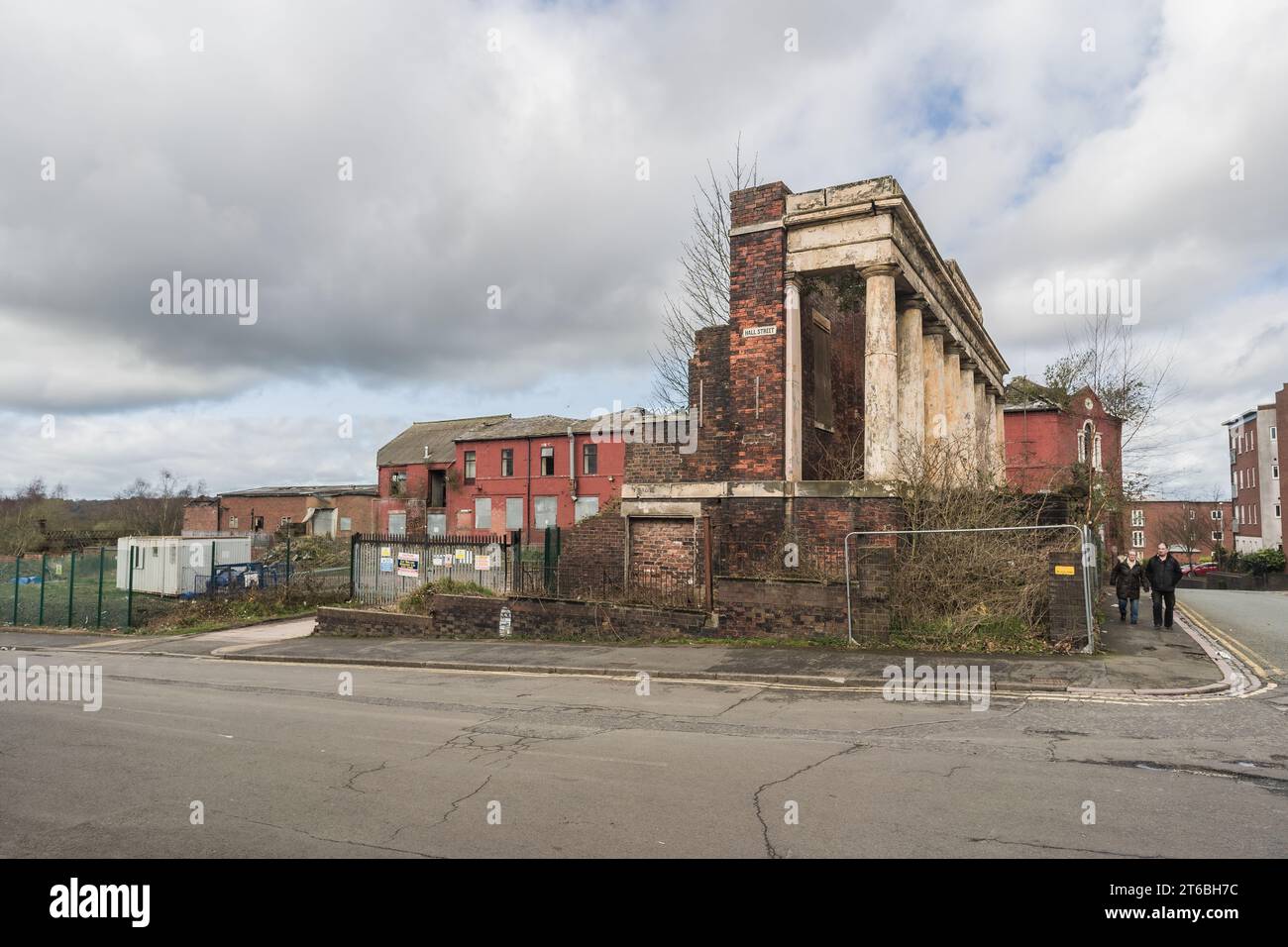 Burslem, Stoke on Trent, England, March 21st 2023. Elderly couple walking past Sunday School ruins with closed Wade pottery factory in background. Stock Photo