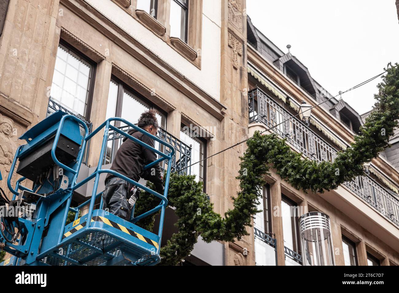 Picture of a man on an aerial lift platform installing christmas decorations and preparing the nye holiday celebrations. Stock Photo