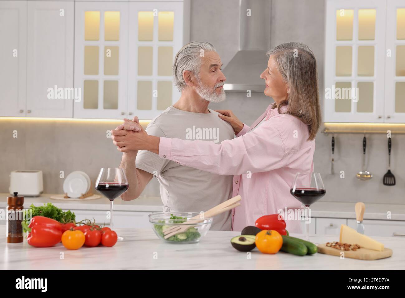Happy affectionate senior couple dancing in kitchen Stock Photo