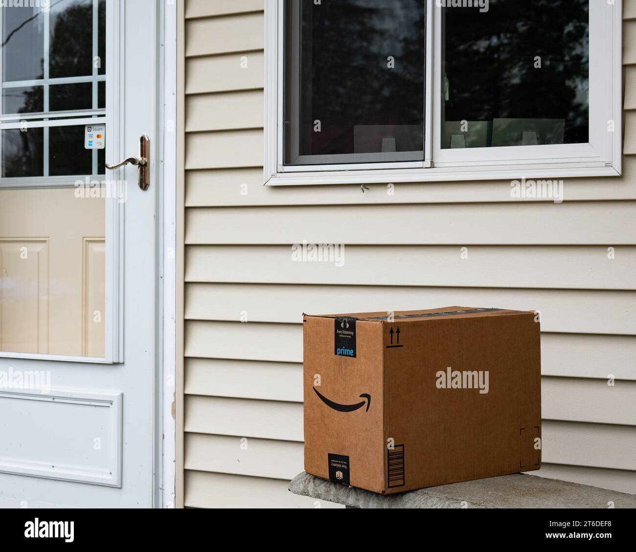 An Amazon Prime delivery box left on a bench by a door Stock Photo