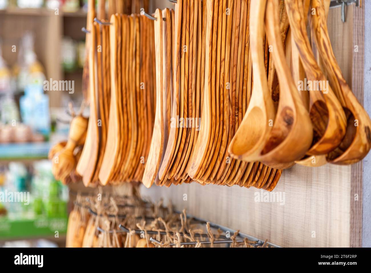 Handmade kitchen utensil, handicraft wooden cutlery hanging outdoors of souvenir store on blur background. Greek traditional souvenir sale Stock Photo