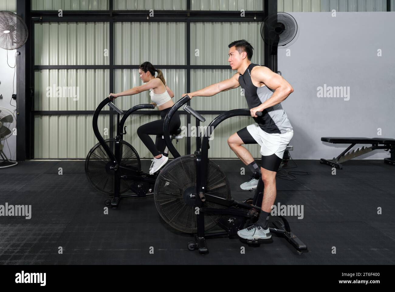 Fitness Couple Cycling on Stationary Bikes in Health Club Stock Photo