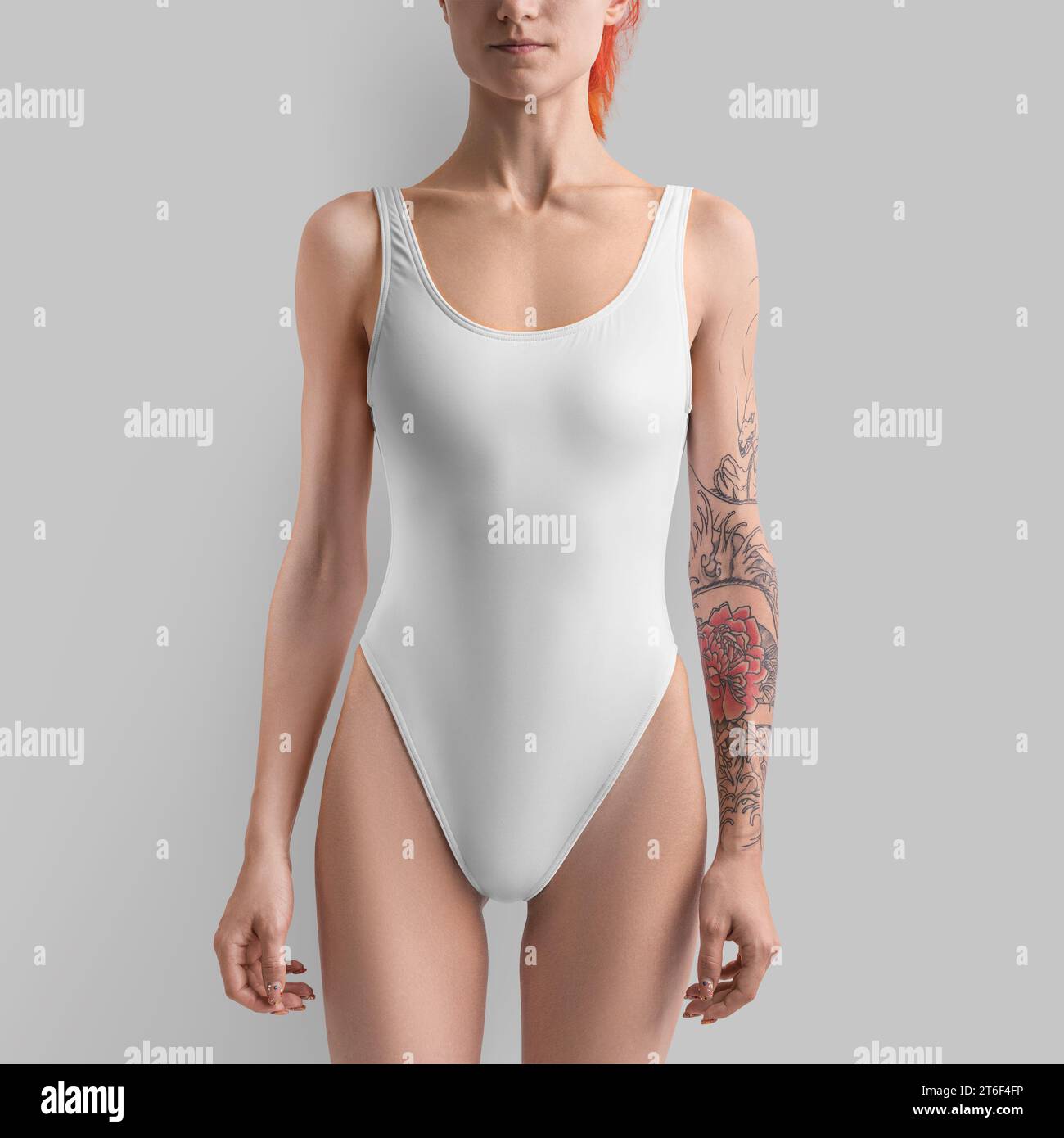 Mockup of white sports swimsuit on red-haired girl, front view, slender model in bodysuit, isolated on background. Template of stylish swimwear for th Stock Photo