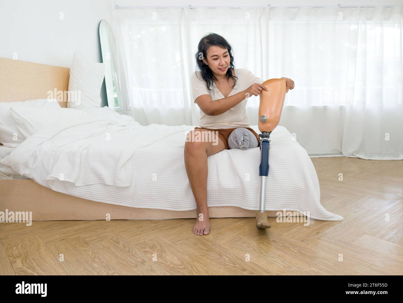 Empowered Women Embracing Life. A determined woman sitting comfortably on a bed, her radiant smile reflecting strength and resilience, while showcasin Stock Photo