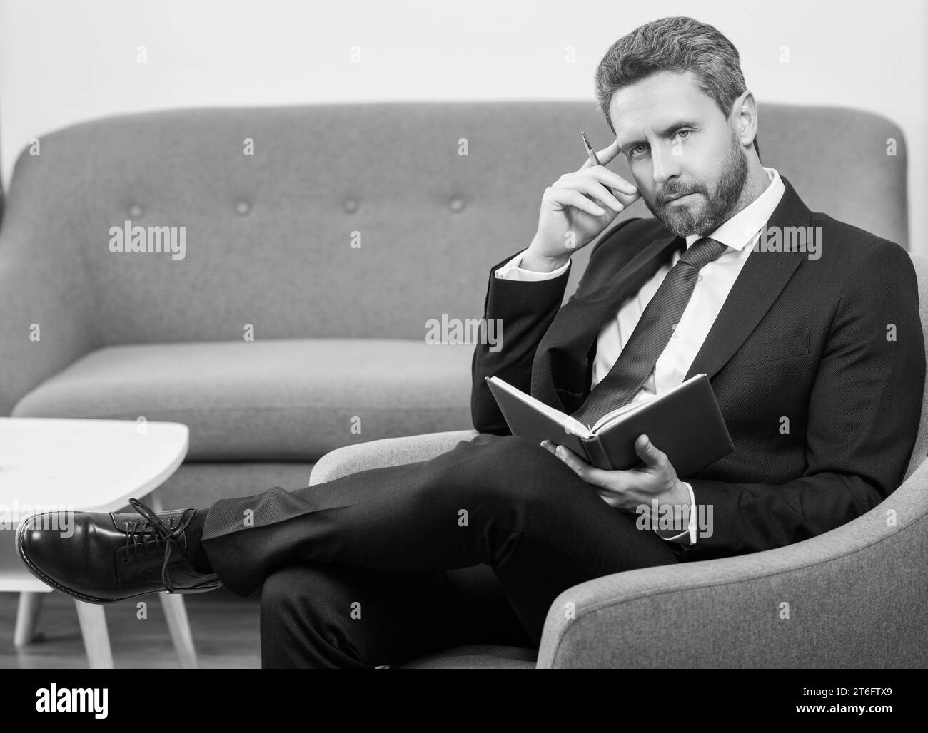 busy mature businessman in suit sit in office making notes in notebook. Stock Photo