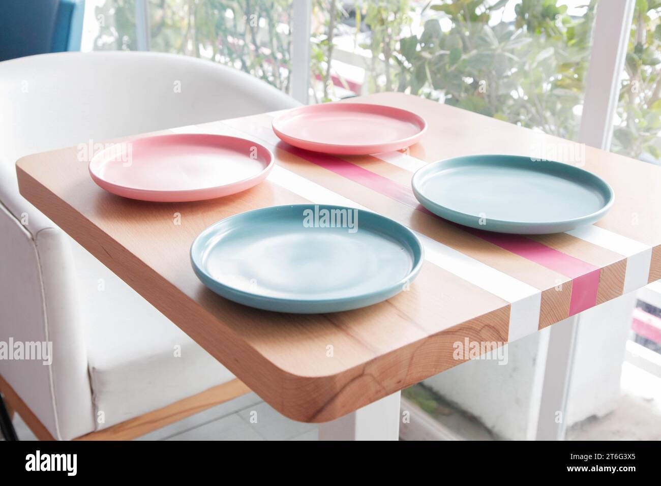 Colourful empty plates on a wooden table at a coffee shop. Stock Photo