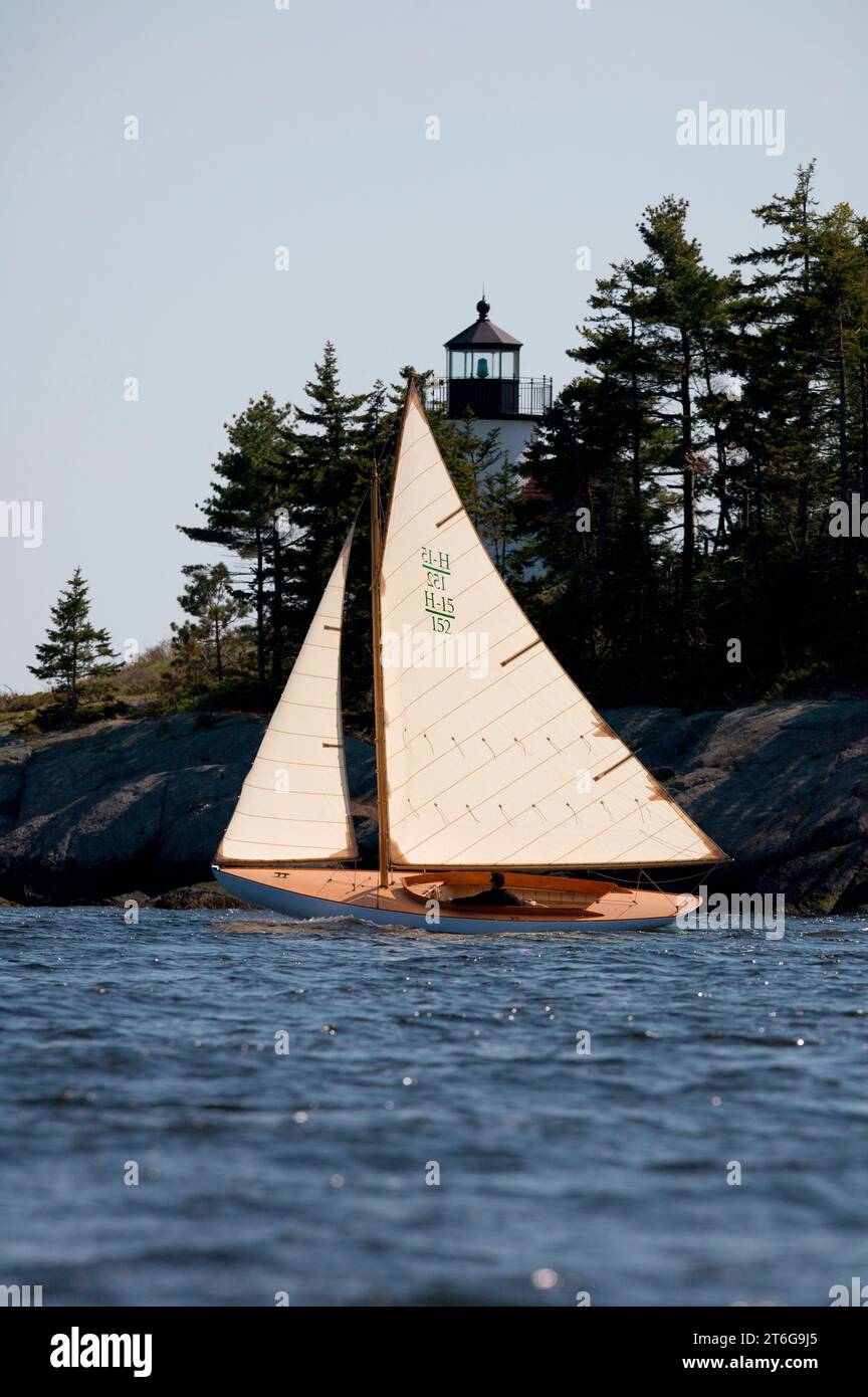 Man sails off the coast of Maine with Curtis Island Light in the background on daysailer Stock Photo