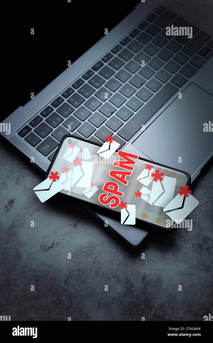 Smartphone laying on laptop with hologram mail spam concept. Communication business technology. Protect spam mail from internet cyber security. Stock Photo