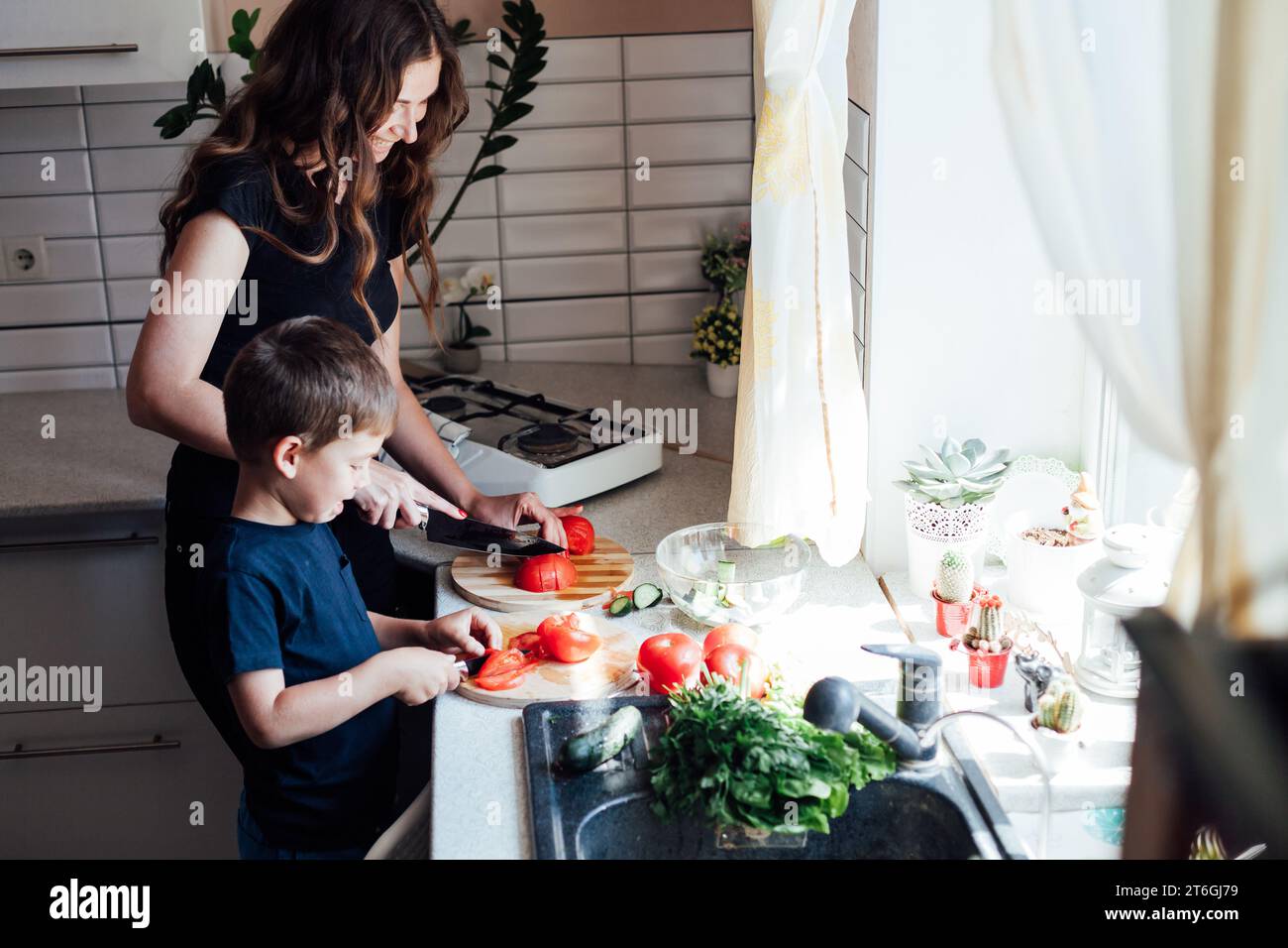 Woman housewife with son cooking food dinner in kitchen Stock Photo