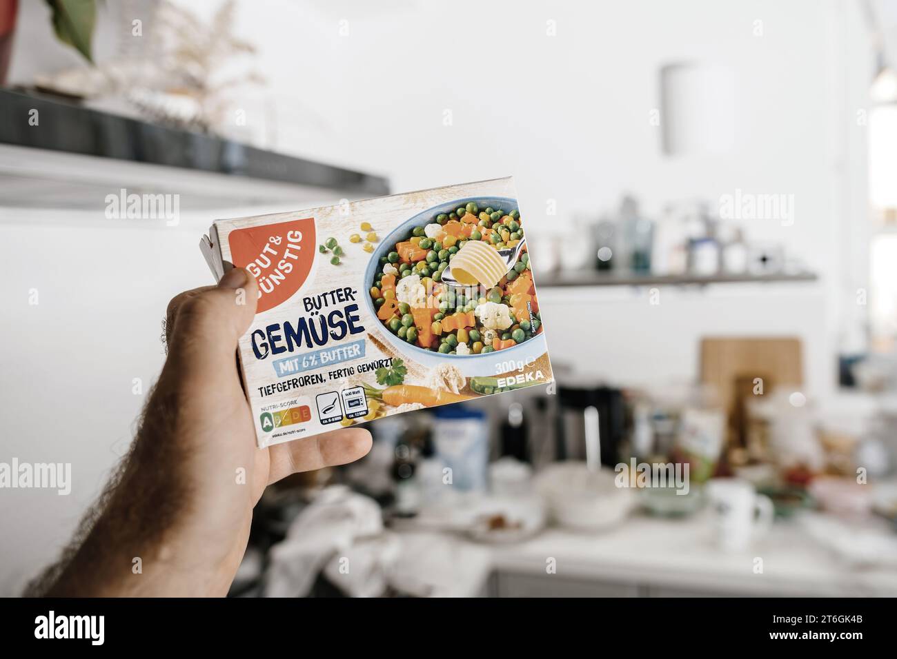Frankfurt, Germany - Jun 12, 2023: A male hand holds a package of frozen Gut and Gunstig Edeka Butter Gemuse in a modern kitchen, ready for a delicious meal Stock Photo