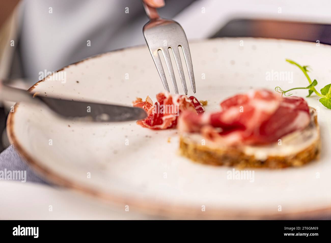 Person eating bruschetta with prosciutto in restaurant Stock Photo