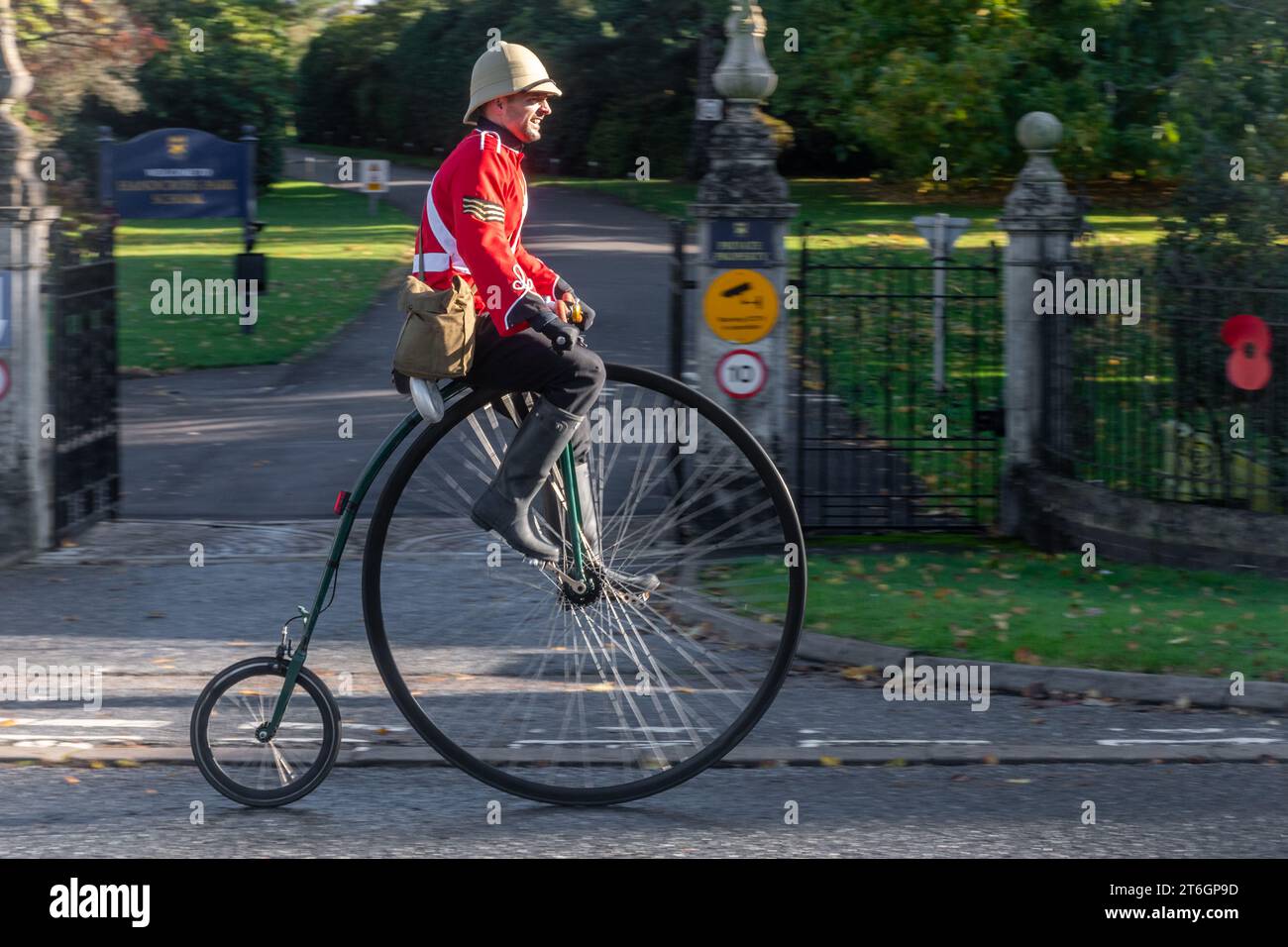 Man riding penny farthing bicycle wearing Victorian British Army tunic and helmet in the London to Brighton veteran car run event, 5th November 2023 Stock Photo