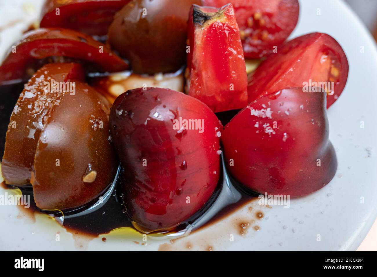 selective focus, sliced tomatoes in a dish with salt and Modena vinegar Stock Photo