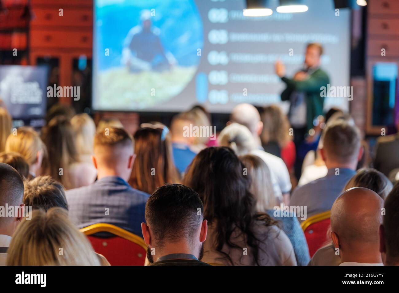 Back view of multiethnic business professionals listening to speaker giving presentation in conference hall Stock Photo
