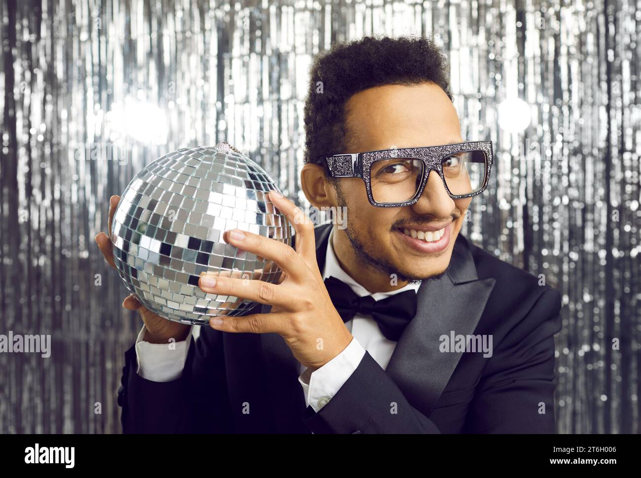 Portrait of elegant and positive young dark-skinned man with disco ball in his hands. Stock Photo