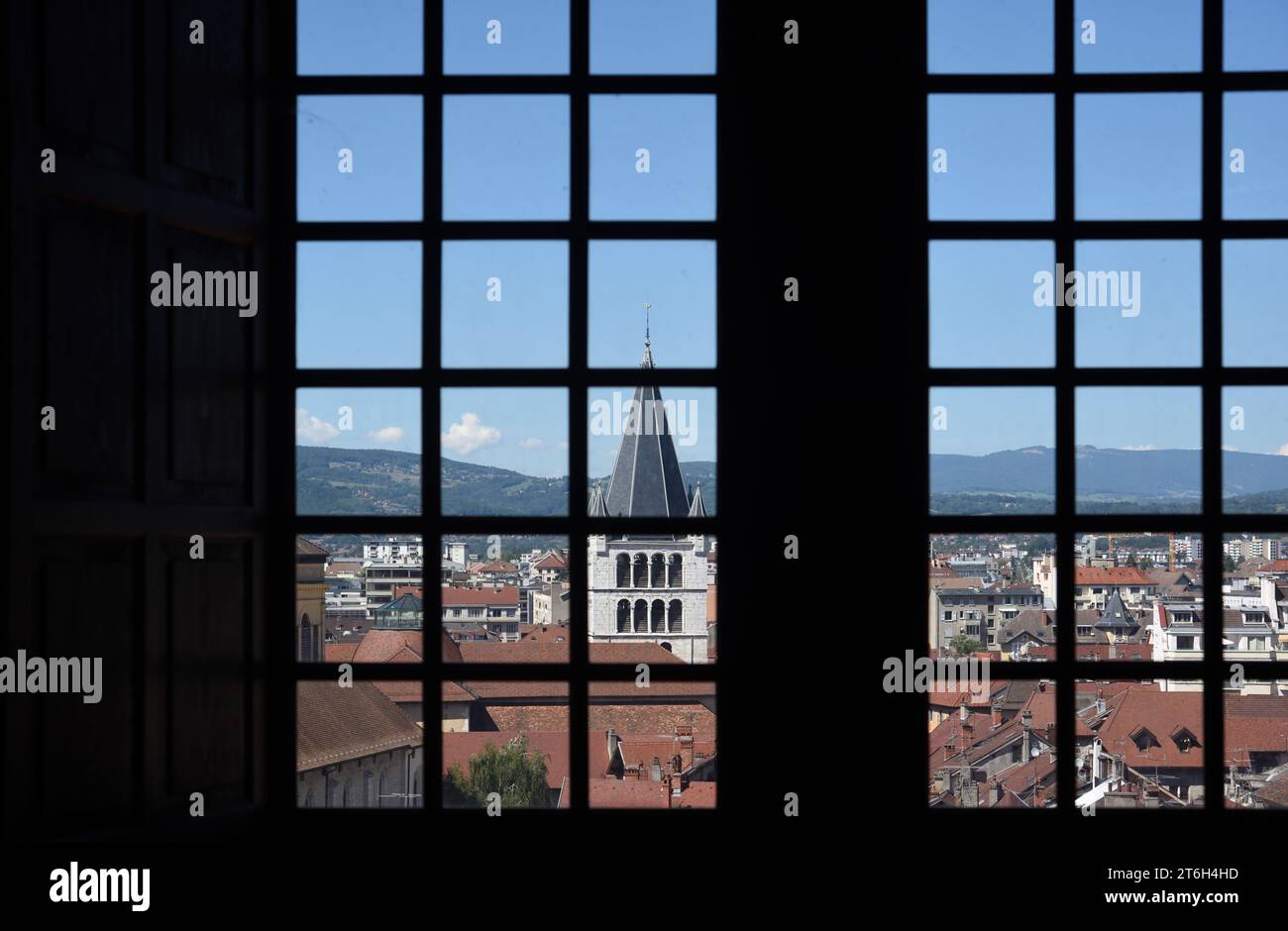 Distorted of Deformed View of the Skyline and Rooftops of the Old Town or Historic District of Annacy Haute Savoie France, through Old Paned Window of Annecy Castle or Chateau. With Church Spire or Belfry of the Church or Eglise of Notre Dame de Lisse Stock Photo