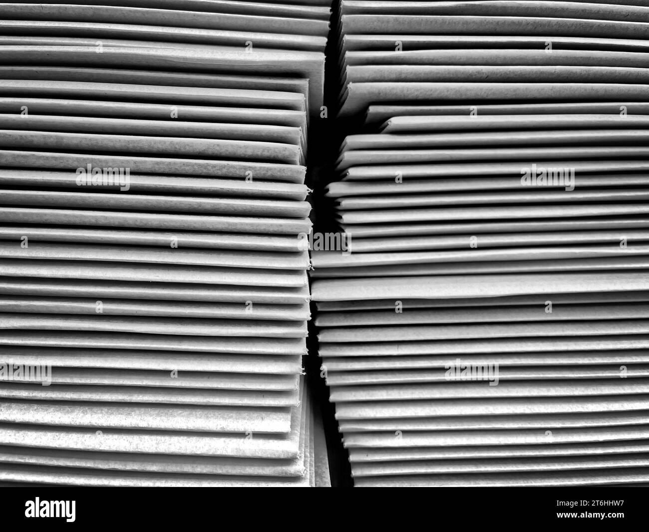 A pile of cardboard boxes are placed side by side in a warehouse setting, illuminated by a dim light source Stock Photo