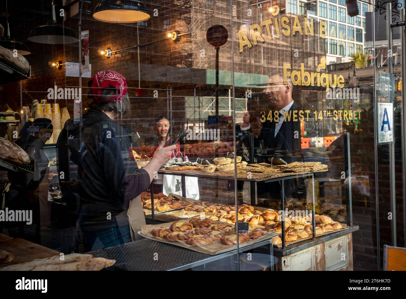 Customers order pastries and other baked goods in the window of Fabrique French bakery in the